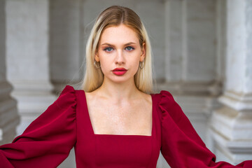 Portrait of a young beautiful blonde girl in an evening burgundy dress