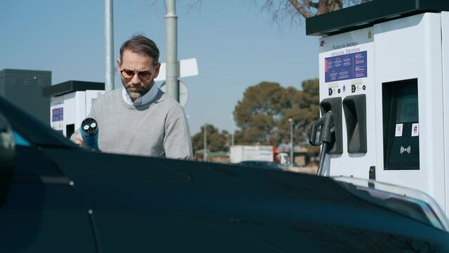 Video of elegant man charging electro car at the electric gas station