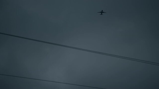 Low angle shot of airplane flies in the night sky over parallel power lines