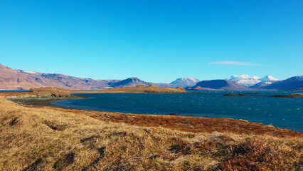 Spectacular lake and snowy mountains in iceland, beautiful clean icelandic nature. Massive water spot with hills and fields creating scandinavian panoramic view, nordic scenery. Handheld shot.