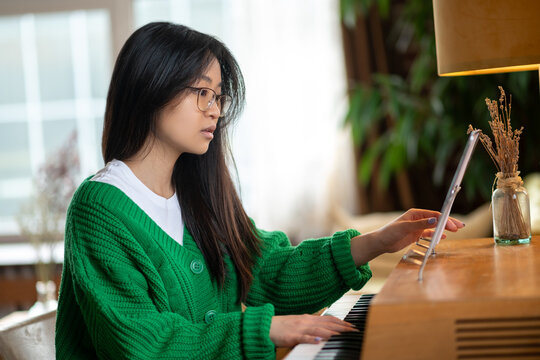 Asian cute girl scrutinizing the music sheet and looking involved