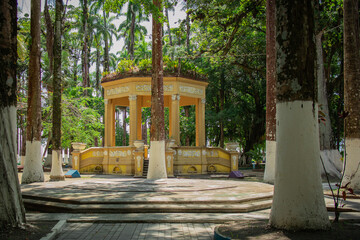 Pavillion in the central park of port city of Limon in costa rica on a sunny day. Visible high palms and other trees and beautiful vintage pavilion in the middle.