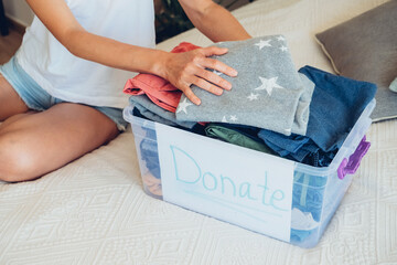 Woman sorts wardrobe indoors at home. Charity donation concept. High quality photo