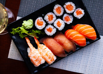 Various sushi served on black plate. Japanese food, nobody