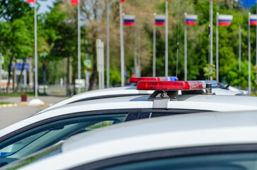 Fototapeta na wymiar Police car flashing light. In the background, the flags of Russia are out of focus.