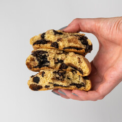 hand holding dark chocolate chip cookies on white background