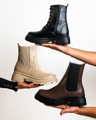 hands holding a set of three leather Chelsea boots 