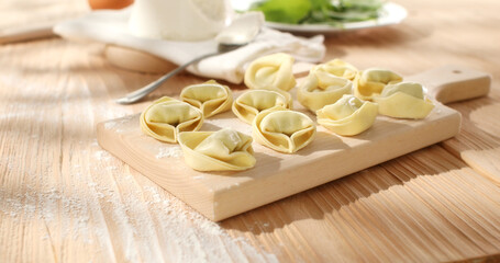 raw tortelloni with spinach on a wooden board. fresh pasta with ricotta cheese and green leaves. traditional italian food. dish mediterranean cuisine.