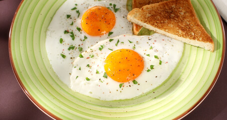 fried eggs with toast on a green plate. close-up. angle view. camera tracking. colored background. traditional breakfast. sunny day.
