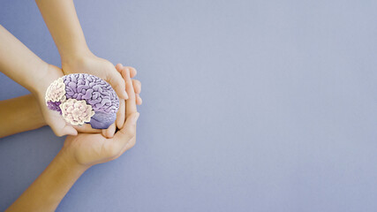 Hands holding purple brain paper cutout, Epilepsy and alzheimer awareness, seizure disorder, world...