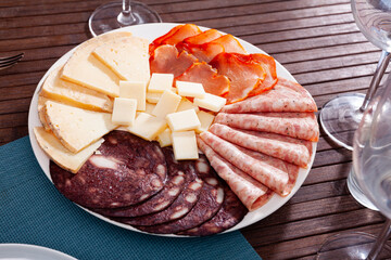 Delicious meat platter - sliced dry-cured pork loin, salami, blood sausage and cheese on serving...