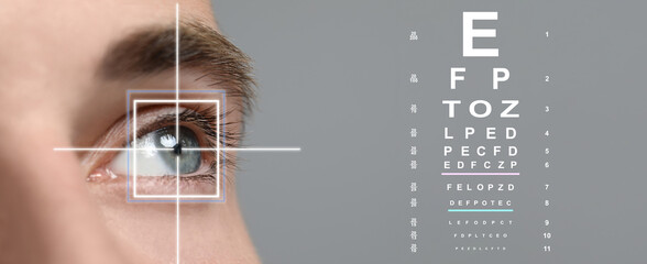 Vision test chart and laser reticle focused on man's eye against light grey background, closeup....