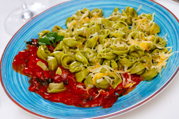 Italian tortellini pasta with spinach and ricotta served with tomato sauce and grated cheese