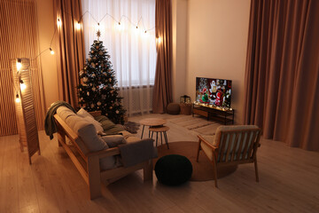 Wide TV set, furniture and Christmas tree in stylish room