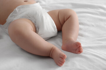 Little baby in diaper lying on bed, closeup - obrazy, fototapety, plakaty