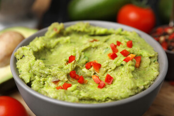 Bowl of delicious guacamole on table, closeup