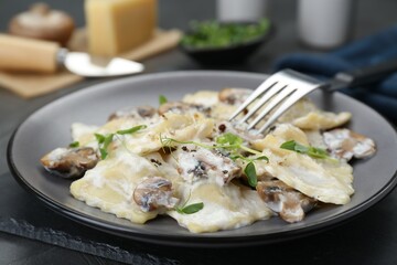Delicious ravioli with tasty sauce and mushrooms served on table, closeup
