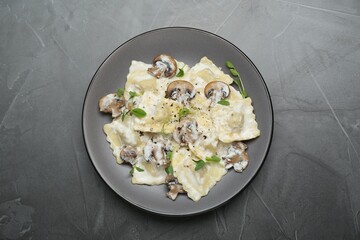 Delicious ravioli with tasty sauce and mushrooms on black table, top view