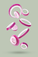 Fresh red onion rings falling on light grey background