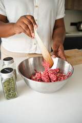 Close up of cuban woman hands mixing raw minced beef and garlic.
