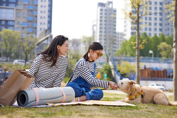 강아지에게 간식을 주는 딸과 함께 앉아있는 엄마