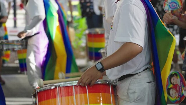 Musicians playing drums having fun and celebration in pride parade. Rainbow colored drum represents the symbol of LGBTQ