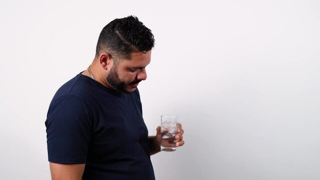 un hombre en fondo blanco tomando agua con hielo - Un hombre se deleita con un sorbo de agua fr&iacute;a - Un momento de tranquilidad con un hombre bebiendo agua con hielo - La pureza del agua