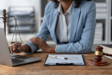 American woman lawyer or businesswoman African working with laptop, searching, analyzing data, reading contract documents work with law books hammer of justice Consulting lawyer concept.