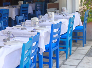 A vacant table with blue chairs at an outdoor waterside cafe in Bodrum, Turkey, May 2023.