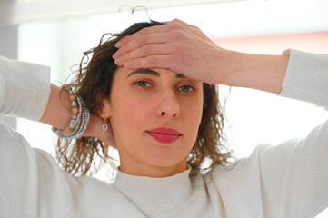 Pretty female with headache holding  hands on the head. Working out the meridians of the head to...