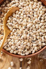 Raw Organic Black Eyed Peas close-up in a bowl on a wooden table. Vertical top view from above