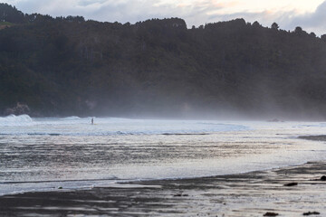 Man surfing the waves with a paddle board in Whangamata Beach