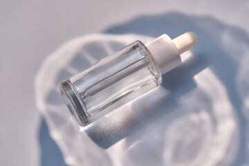 Serum bottle on a blue background with glare.