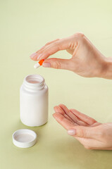A woman's hand takes a pill out of a pill bottle. The empty white bottle for packaging medicines. Mockup. Space for logo and text.