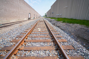 Fototapeta na wymiar Railway line running between building in industrial area