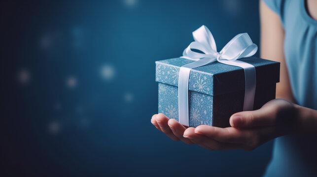 Female hands holding Christmas gift box on Blue background