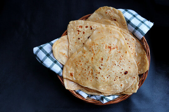 Triangle shape Plain Parotha or namak Parantha or tel paratha is an Indian flatbread made of whole-wheat flour, salt, and oil. served in a wooden basket. copy space.