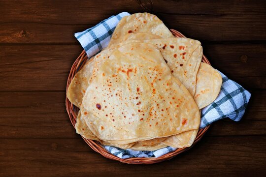 Triangle shape Plain Parotha or namak Parantha or tel paratha is an Indian flatbread made of whole-wheat flour, salt, and oil. served in a wooden basket. copy space.