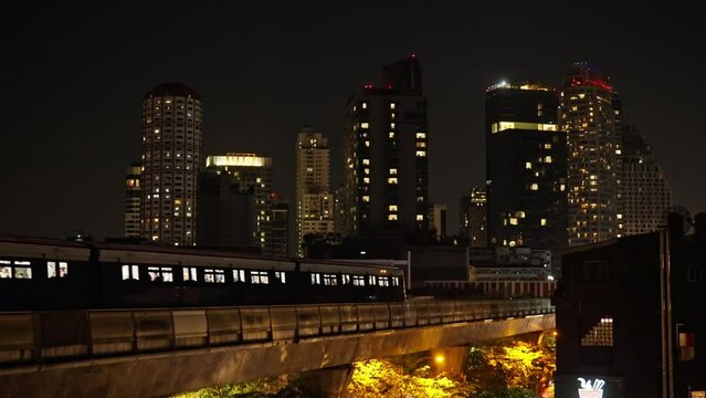 A Train Crosses A Railroad Bridge In Bangkok At Night