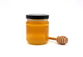 Jar of honey with wooden honey spoon isolated on white background.