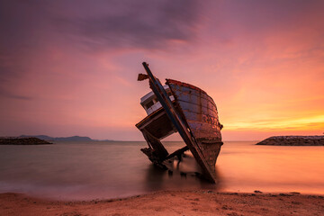 Shooting in long exposure of old shipwreck boat abandoned stand on beach with beautiful sunset at Pattaya in the eastern, Thailand