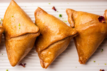 Indian sweet samosa is a Fried pastry soaked in sugar syrup filled with coconut, nuts and fruits