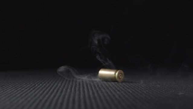 Slow motion shot of empty bullet shells fall down on a black background. 
