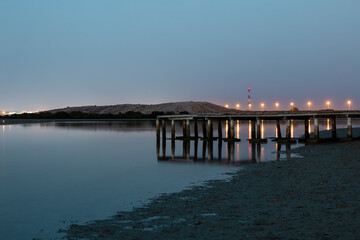 Fototapeta na wymiar Beautiful after-sunset shot of a lake with a wooden footbridge, captured from a mangrove beach in Umm Al Quwain, United Arab Emirates.