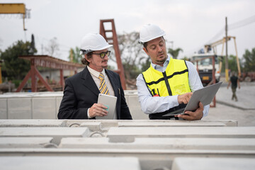 Portrait two caucasian engineer man working with notebook computer at precast site work	