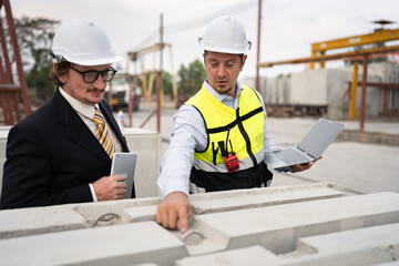 Portrait two caucasian engineer man working with notebook computer at precast site work	