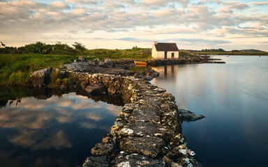 Beautiful morning landscape scenery with fisherman's hut and old wooden reflected in lake by the stone pier at Screebe, connemara national Park in County Galway, Ireland 