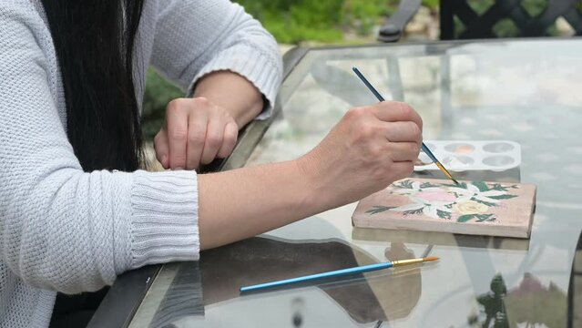 Video clip of woman enjoying painting on canvas outdoors as a hobby