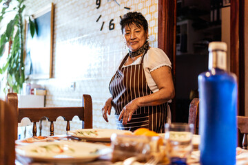 Fototapeta na wymiar older latin american woman putting things to eat on the table
