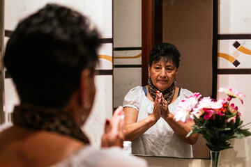 older latin american woman putting cream on her face